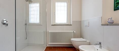 Une salle de bain équipée d’une douche, de toilettes, d’un bidet et d’un radiateur.