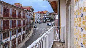 A street view from a balcony with buildings featuring traditional architecture and a cobblestone street. - Charming Porto Apartment with City and River Views (Porto)