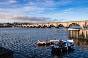 A bridge over a river with boats docked nearby.