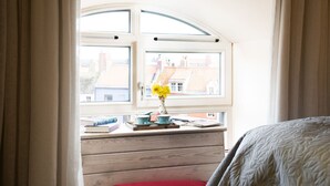 Een kamer met een houten bureau, een rode bank en een raam met uitzicht op gebouwen.