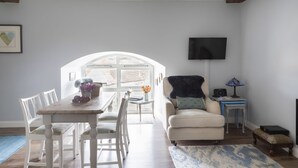 A modern living room with a dining area, a sofa, a TV mounted on the wall, and a window with a view. - THE MEETING HOUSE in the centre of Berwick-upon-Tweed (Berwick-upon-Tweed)