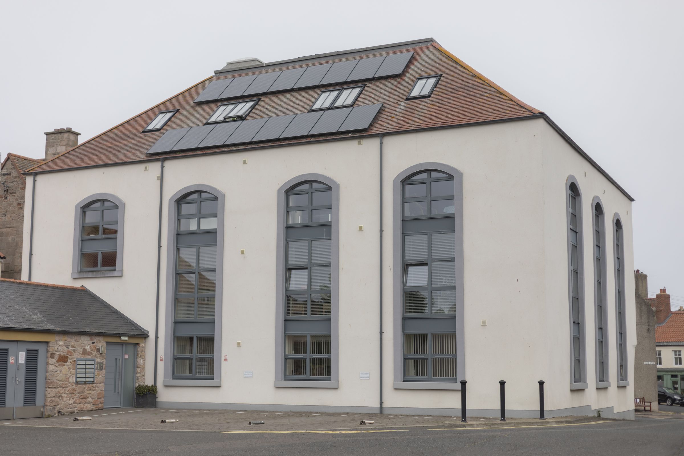 A building with large windows and a sloped roof with solar panels.