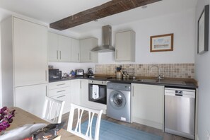 A compact kitchen with white cabinets, a built-in oven, a washing machine, and a dishwasher.