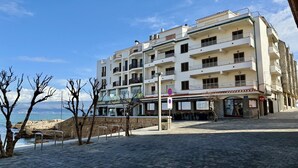 Ein mehrstöckiges Hotel mit Balkonen, ein Restaurant im Erdgeschoss und Blick auf das Meer.