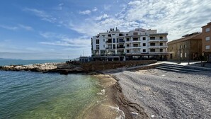 Ein Küstengebäude mit mehreren Balkonen, einem Steinweg und Blick auf das Meer.