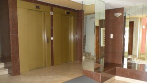 A hotel lobby with a marble floor, a glass elevator, and a set of double doors. - GIJON (1 BEDROOM) BENIDORM (Benidorm)