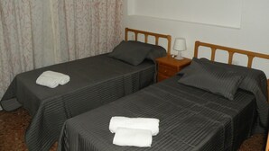 A hotel room with two single beds, each with a pillow and a folded towel. There is a nightstand with a lamp between the beds. - GIJON (1 BEDROOM) BENIDORM (Benidorm)