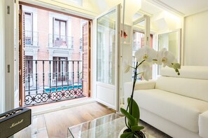 Una sala moderna con un sofá blanco, una mesa de centro de vidrio y orquídeas blancas.