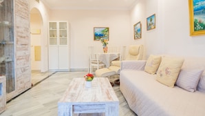 Una sala de estar moderna con un sofá blanco, una mesa de centro de madera y un comedor con una mesa y sillas blancas.