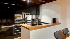 Eine moderne Küche mit Holzarbeitsplatte, Edelstahlgeräten und einer Kaffeemaschine.