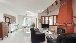 Un salon spacieux avec cheminée, un coin repas baigné de lumière naturelle et une cuisine équipée d’appareils modernes.