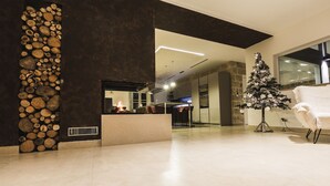 Ein modernes Interieur mit Steinwand, Kamin, Weihnachtstannenbaum und weißem Ohrensessel.