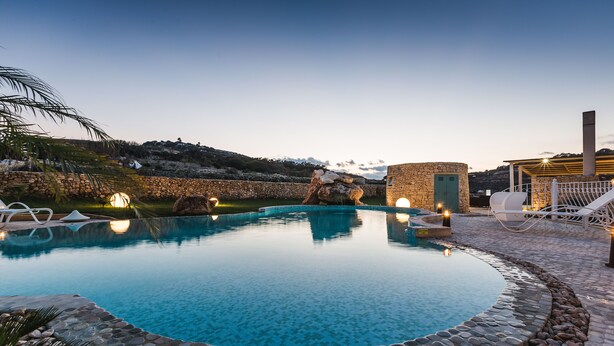 Ein Pool mit Steinrand, Liegestühlen und Blick auf die Landschaft.