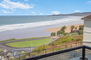 Vista costera con playa, zonas verdes y un edificio con techo rojo.