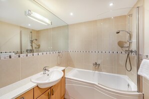 A modern bathroom with a glass-enclosed shower, a freestanding bathtub, and a vanity with a sink.