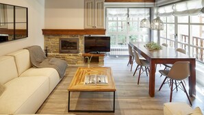 A spacious living area with a fireplace, a television, a dining table with chairs, and a large window providing natural light. - Val de Ruda Luxe 9 by FeelFree Rentals (Naut Aran)
