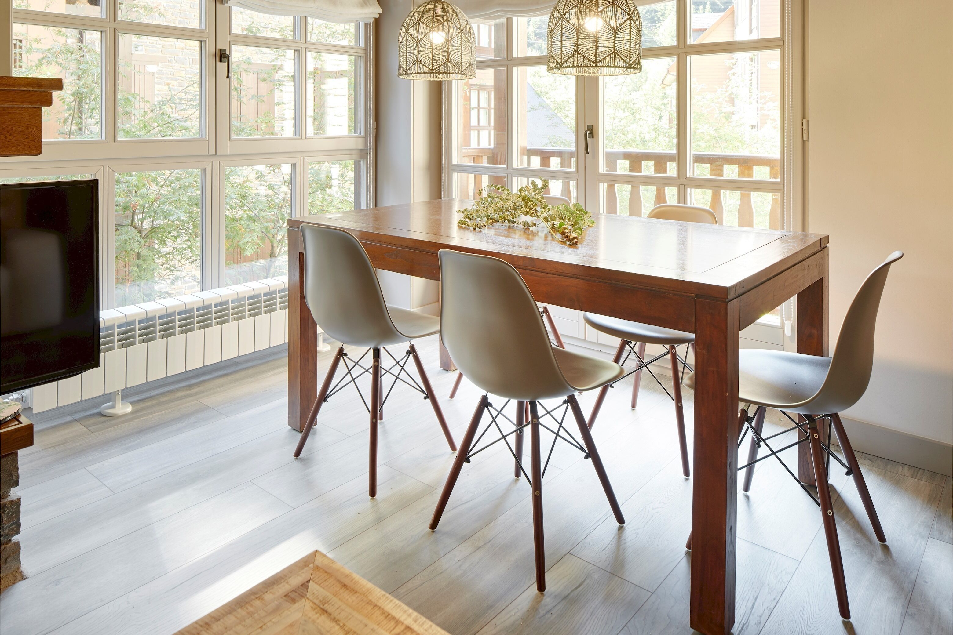 Un coin repas avec une table en bois, quatre chaises et un téléviseur placé sur le côté gauche.