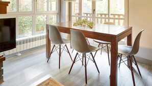 A dining area with a wooden table, four chairs, and a TV on the left. - Val de Ruda Luxe 9 by FeelFree Rentals (Naut Aran)