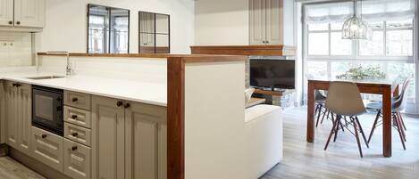 A modern kitchen with wooden beams, a large island, and a dining area with a TV.