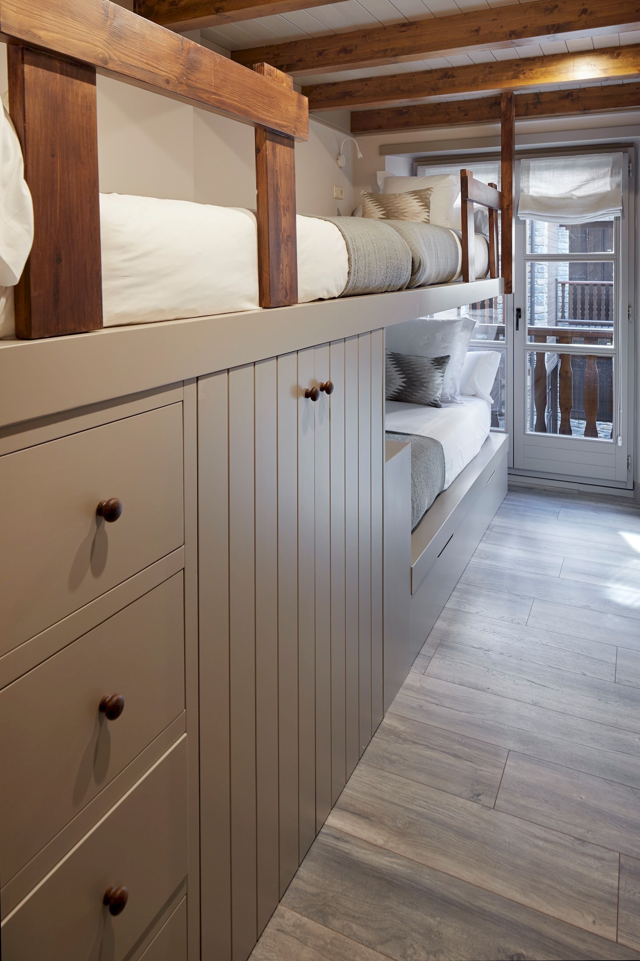 Une chambre avec un lit superposé, des poutres en bois, une porte coulissante et une vue sur le balcon extérieur.