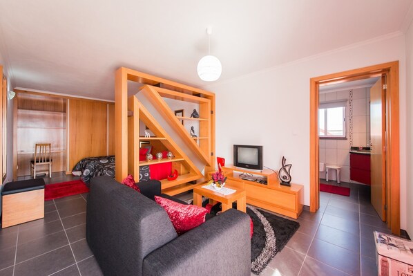 Un salon moderne avec un canapé, une table basse, un téléviseur et une bibliothèque en bois.
