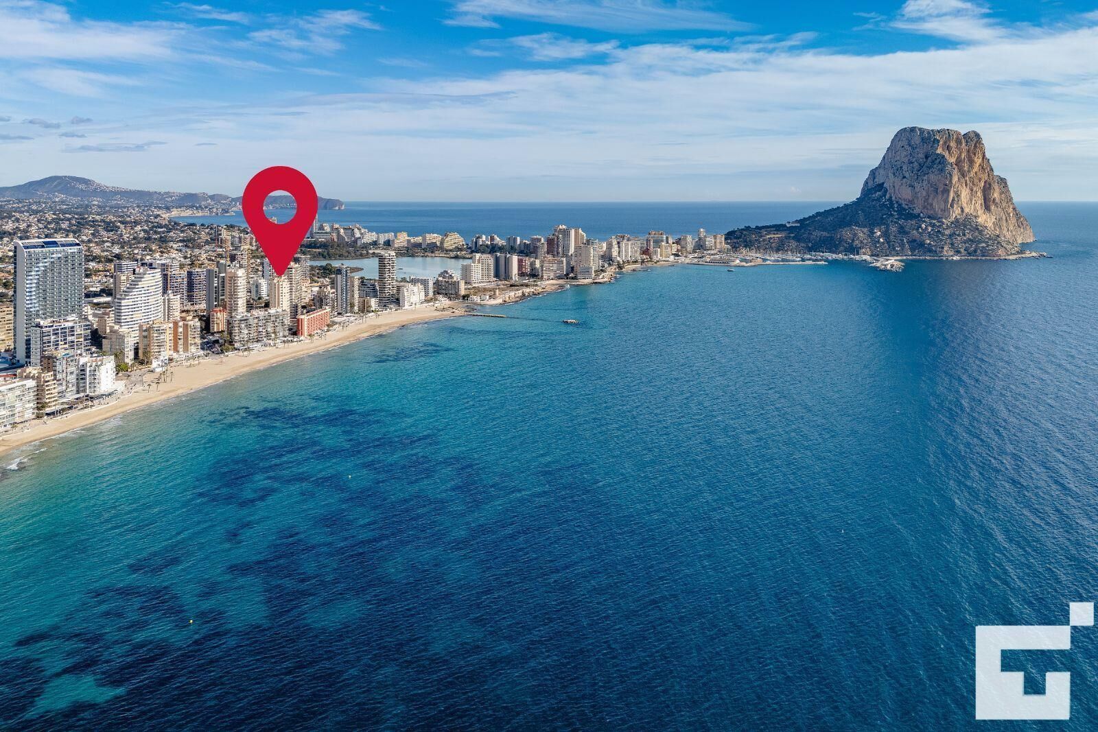 Ein Luftbild einer Küstenstadt mit einem markanten Berg, einem Strand und einem dicht bebauten Stadtgebiet.