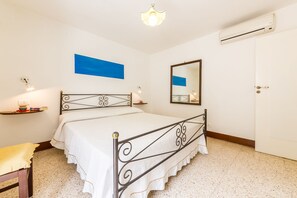 A neatly arranged bedroom with a bed, a bedside table, a wall-mounted shelf, a mirror, and an air conditioning unit. - Rooftop house in the center, 2/4 guests, free illimited WIFI, free parking (Scicli)