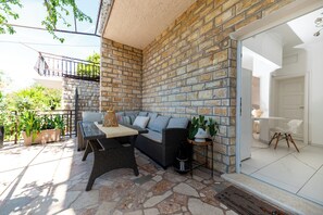 Un patio con un sofá, una mesa de mimbre y plantas en macetas.