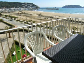 A balcony with white chairs and a black table overlooking a beach and a parking lot. - ROCAMAURA I B 6-1 (Estartit)