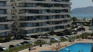 A multi-story building with balconies, a swimming pool, and a beach area with sun loungers. - ROCAMAURA I B 6-1 (Estartit)