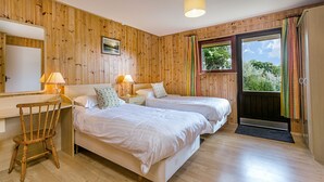 Une chambre avec deux lits, un bureau et une chaise. Il y a une fenêtre avec des rideaux et une porte.