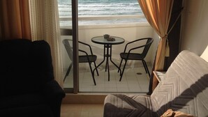 A room with a view of the ocean, a sofa, a small table with chairs, and curtains. - The Perfect Sea View apartment let you enjoy the facilities and benefits of livi (Bat Yam)