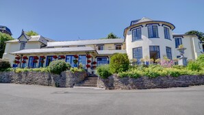 A two-story building with a stone facade, a curved corner section, and a staircase leading to the entrance. - 2 Bed in Lynton (oc-cslewt) (Lynmouth)