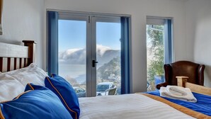 A hotel room with a bed, a chair, and a view of a mountain and a car through the window. - 2 Bed in Lynton (oc-cslewt) (Lynmouth)