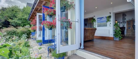 Una casa moderna con un sendero de piedra, cestas de flores colgantes y un interior de madera.