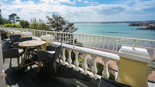Une terrasse dotée de meubles en osier et offrant une vue sur la mer.