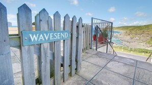 A wooden gate with a sign reading "WAVESEND" leading to a beach area with a metal railing overlooking the ocean. - 1 Bed in Woolacombe (oc-waves) (Woolacombe)