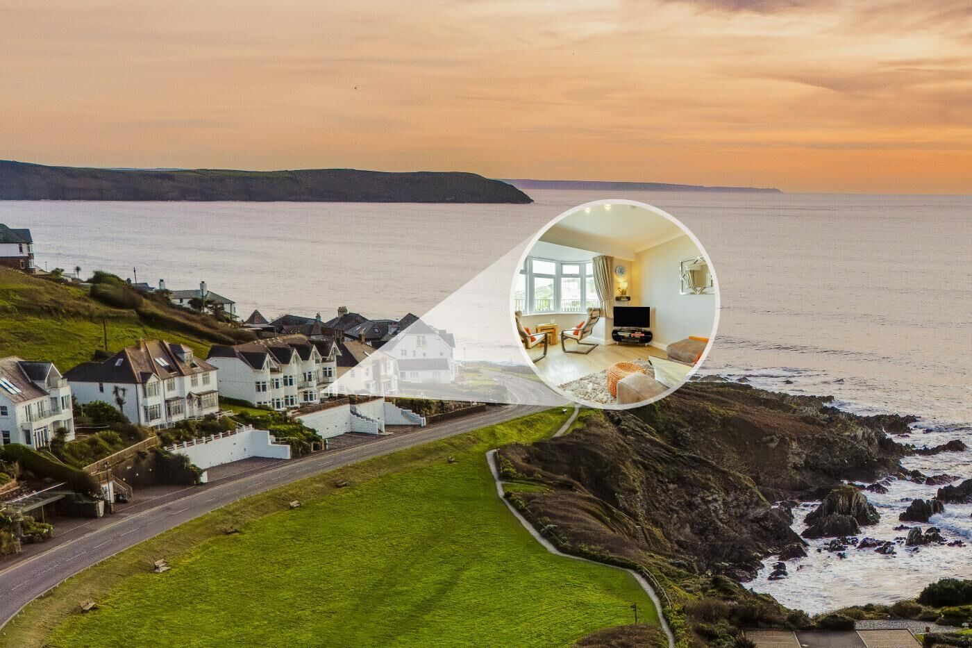 A coastal property with a view of the sea, a lawn, and a road leading to the sea.
