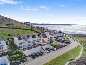 Uma área residencial costeira com casas, uma estrada e vista para o mar.