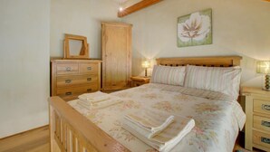 Een slaapkamer met een houten bed, een nachtkastje met een lamp, een dressoir en een garderobe.