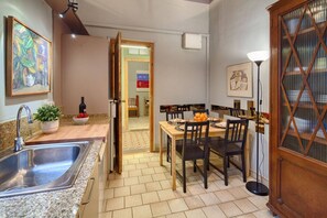A kitchen with a sink, countertop, and dining area with chairs and a table.