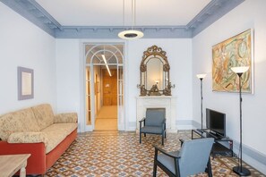 A living room with a sofa, chairs, a fireplace, a television, and a painting.
