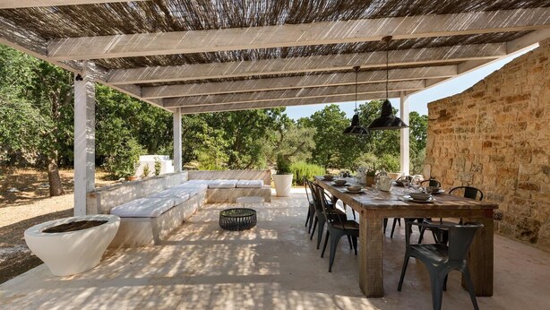 An outdoor patio with a dining table, chairs, a sofa, and a pergola.