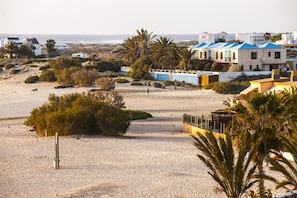 A beach with buildings, palm trees, and a sandy area.
