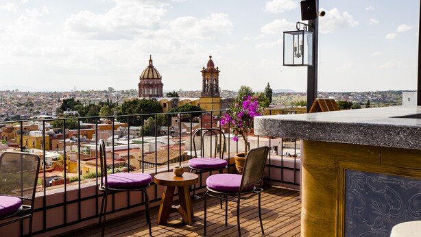 Una terraza con vistas a un paisaje urbano, que incluye una iglesia destacada y una torre del reloj.