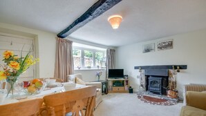 Una sala de estar acogedora con chimenea, una mesa de comedor con sillas y un televisor.