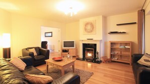 A living room with a fireplace, leather sofas, a coffee table, and a bookshelf.