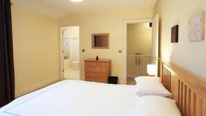 A bedroom with a large bed, wooden dresser, and a mirror on the wall.