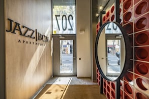 A hallway with a wooden wall, a mirror, and a door with the word 'JAZZ' partially visible. - Hot Jazz 32 - Habitat Apartments (Barcelona)