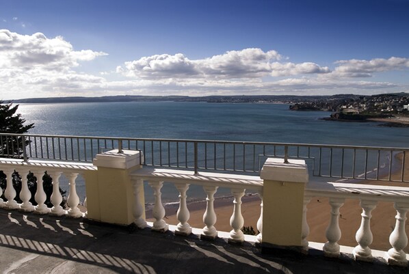 Un balcon avec vue sur la mer et sur une côte lointaine.